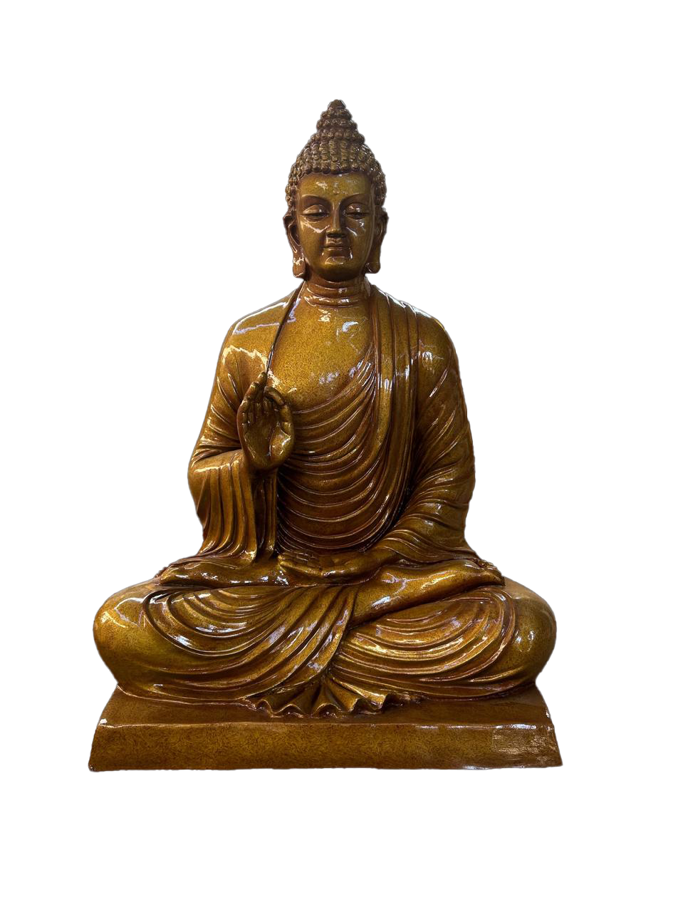 Majestic Buddha statue in a bronze metallic finish, seated in lotus posture on a decorative pedestal, placed outdoors in a lush garden with tropical trees and greenery.