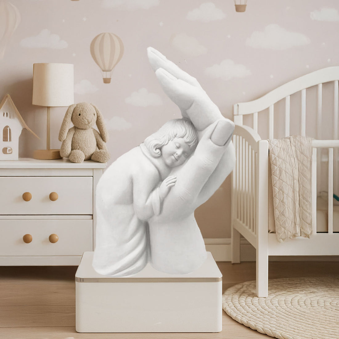 White handcrafted sculpture of a child peacefully resting in a protective hand, symbolizing care, safety, and love, placed in a serene nursery setting.