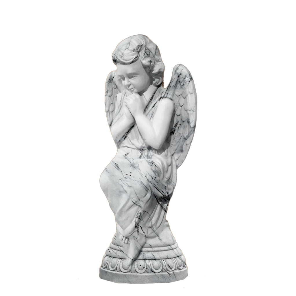 Graceful praying angel sculpture in a white marble finish with fine detailing, displayed indoors on a pedestal in a luxury hall with chandelier lighting.