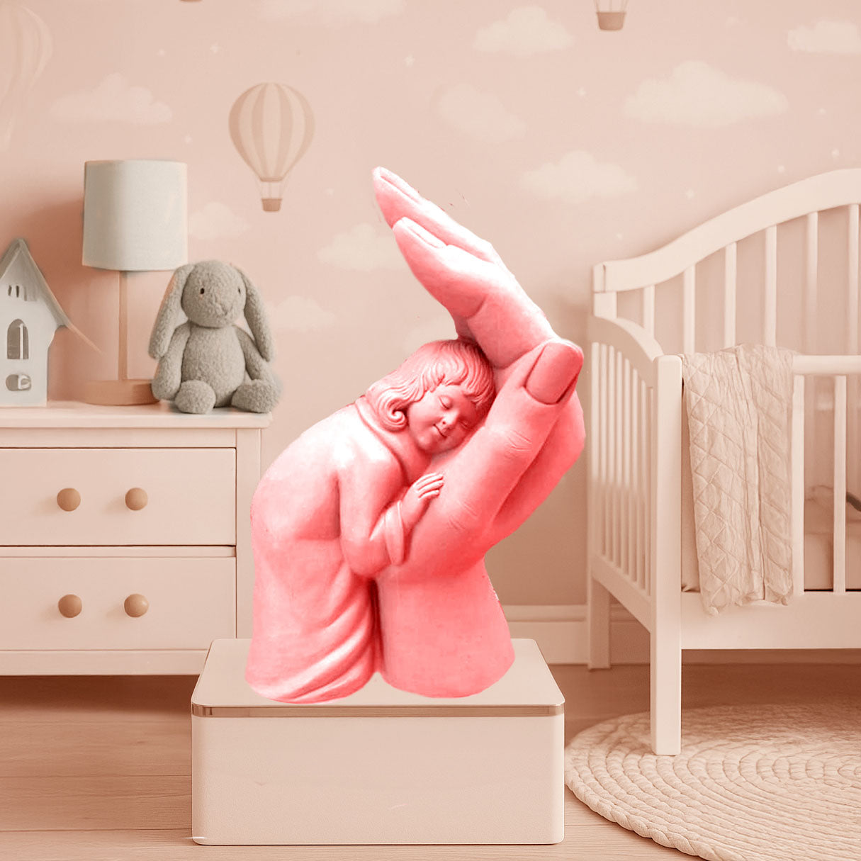 Artistic pink sculpture of a child peacefully resting in a protective hand, symbolizing love, safety, and comfort, styled in a soft nursery room setting.
