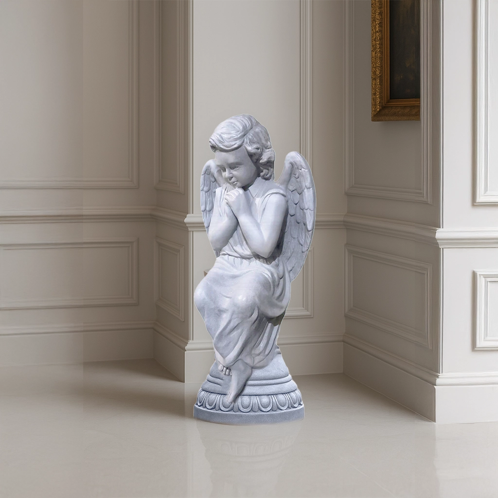 Beautiful praying angel sculpture in a smooth marble finish, with delicate wings and serene detailing, placed indoors in a luxury white-paneled interior.