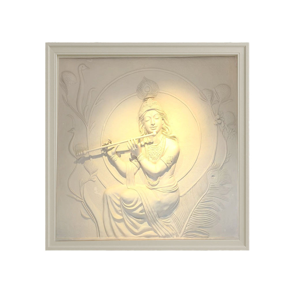 Intricately crafted white marble-finish wall mural depicting Lord Krishna playing the flute, surrounded by peacock feathers and floral motifs, radiating divine serenity in a framed setting.
