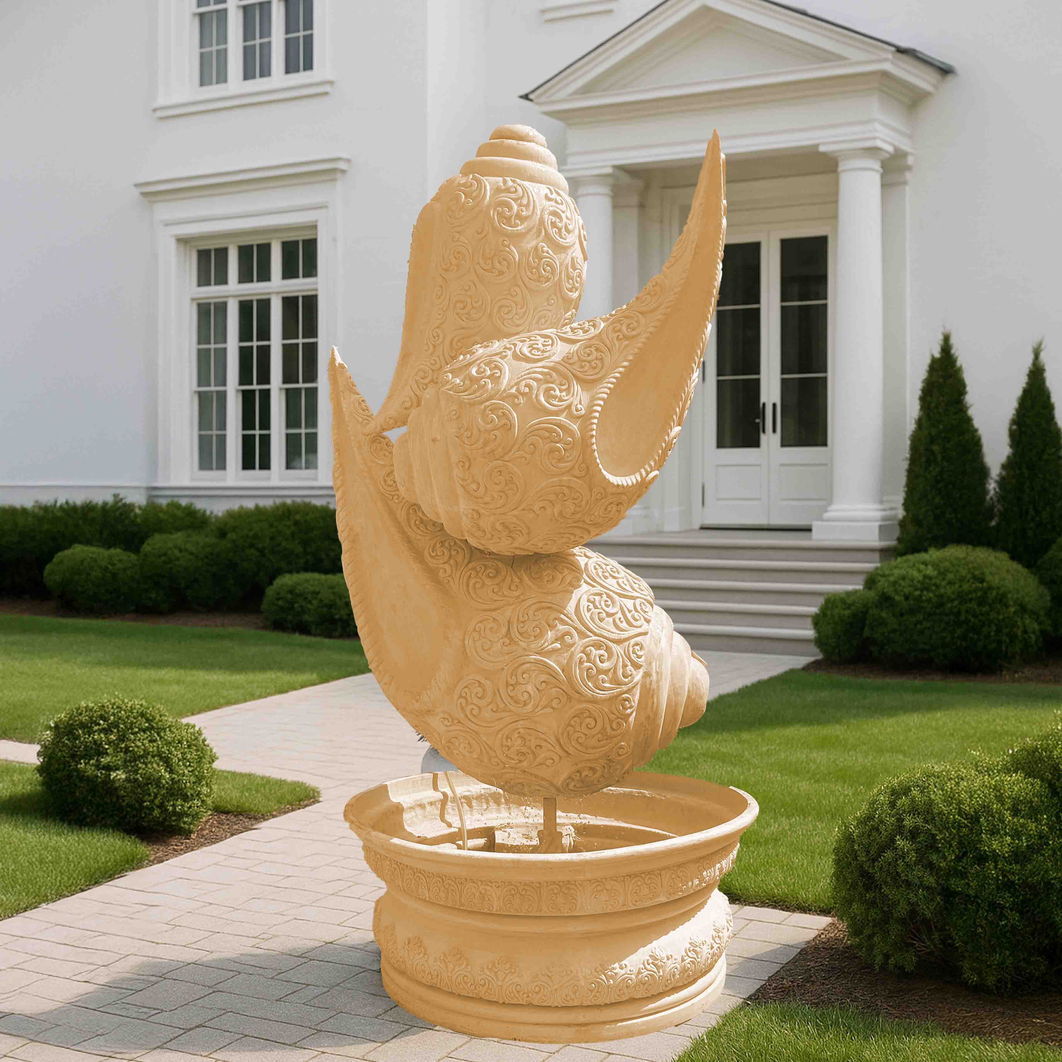 Intricately carved beige stone-finish shankh (conch shell) fountain sculpture with ornate detailing, placed on a decorative pedestal basin in an elegant garden entrance setting.