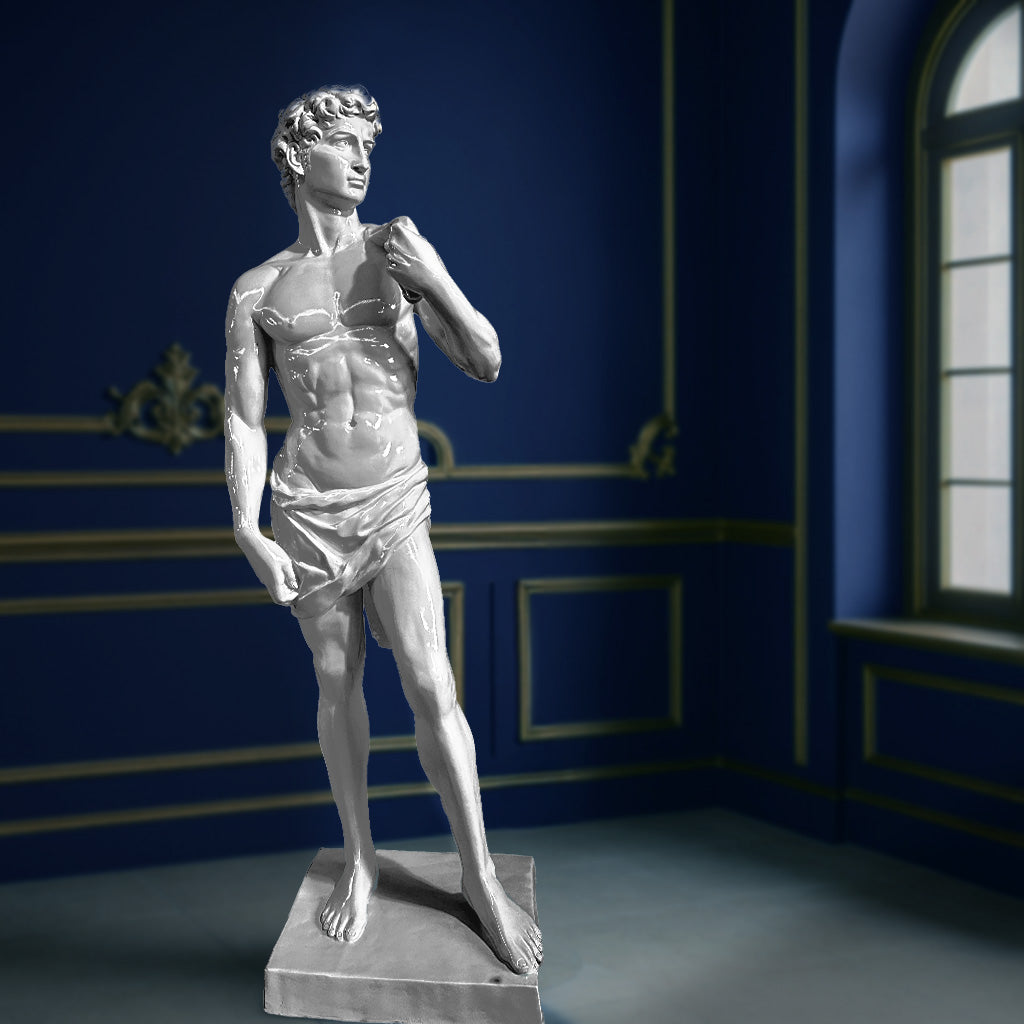 Striking silver-toned sculpture inspired by Michelangelo’s David, displayed in a sophisticated interior with deep blue walls and golden detailing.